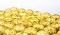 A lot of shiny golden chocolate wrapper in line on white background