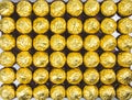 A lot of shiny golden chocolate wrapper in line on white background..