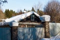 A lot of snow on the roof of an old rural house and on the fence on a sunny winter day Royalty Free Stock Photo