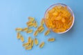 A lot of soft jelly capsules with fish oil as a source of Omega 3 in a transparent bowl on blue background. Concept of health