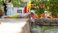 A lot of splashes in park fountain. Little cute boy lying on parapet of fountain