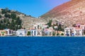 A lot of tiny colorful houses on the rocky shore of Mediterrenean sea on Simy greek island in sunny summer day