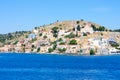 A lot of tiny colorful houses on the rocky shore of Mediterrenean sea on Simy greek island in sunny summer day, tourism Royalty Free Stock Photo