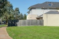 A lot of vacant land with a two-storey suburban house next to it. Melbourne, VIC Australia. Royalty Free Stock Photo