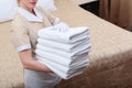 A lot of white clean towels in the hands of the maid. Unrecognizable photo. The concept of the hotel business