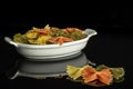 Raw farfalle tricolore isolated on black glass