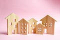A lot of wooden houses on a pink background. The concept of the city or town. Investing in real estate, buying a house. Management