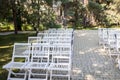 A lot of wooden white chairs near the platform for a wedding ceremony under the open sky. Chairs