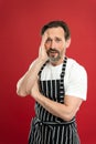 Lot of work. Confident mature handsome man in apron red background. He might be baker gardener chef or cleaner. Good in Royalty Free Stock Photo