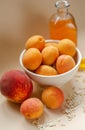 Lots of apricots on a white plate and glass of apricot juice on a white table strewn with oatmeal.
