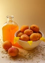 Lots of apricots on a white plate and glass of apricot juice on a white table strewn with oatmeal.