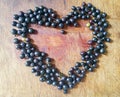 Lots of black currants on a wooden table in the shape of a heart.