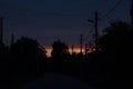 Lots of cables and utility poles silhouettes on the orange sunset background (urban lanscape) Royalty Free Stock Photo