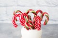 Lots of Christmas candy canes in a mug on a grey background with copy space. Bright festive Christmas caramel