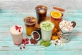 Lots of cold drinks on a light background with decorations of coffee beans, red berries, marshmallows, coconut shavings, orange