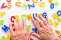 Lots of colorful letters on a table, hands forming german word, keep order