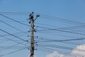 Lots of electrical wires on one concrete pillar. Blue sky, clouds, selective focus