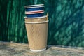 Lots of empty paper coffee cups on a gray wooden board against a green wall
