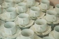 Lots of empty white cups on napkins and saucers