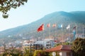 Lots of Europe flags on poles. Mountain in the background and houses nearby. Centered on the Turkey flag. Turkey, Alanya