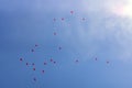 Lots of festive red balloons inflated with helium in blue sunny sky