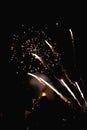 Lots of fireworks popping apart photographed with a vintage lens in a black night and a bonfire in the background Royalty Free Stock Photo