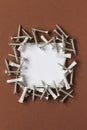 Lots of gray plastic dowels and galvanized metal screws on a brown background