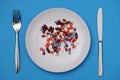 Lots of multi-colored capsule and lying on plate with fork and knife closeup Royalty Free Stock Photo