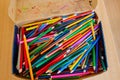 Lots of old colored wooden pencils in a cardboard box with children`s doodles Royalty Free Stock Photo