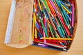 Lots of old colored wooden pencils in a cardboard box with children`s doodles Royalty Free Stock Photo