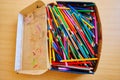 Lots of old colored wooden pencils in a cardboard box with children`s doodles Royalty Free Stock Photo