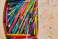 Lots of old colored wooden pencils in a cardboard box with children`s doodles Royalty Free Stock Photo