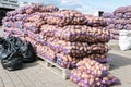 Lots of potatoes in mesh bags on pallets for sale at a farmer\'s market. Wholesale of potatoes