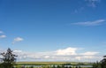 Lots of sky. Landscape overlooking fields, meadows, clouds and a lake.