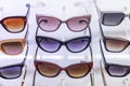 Lots of sunglasses in different shapes and colors on display in a store. Vacation and travel. Close-up. Front view Royalty Free Stock Photo