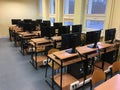 Lots of tables, computers and monitors in the empty classroom
