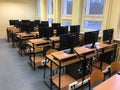 Lots of tables, computers and monitors in the empty classroom