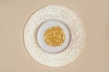 Lots of yellow gel capsules of omega vitamins in round stylish beige plate on wicker round napkin. Monochrome table setting, Royalty Free Stock Photo