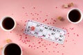 Lotto ticket with wood barrel 14 number and coffee tea cups, sweets candy chocolate on pink hearts background Royalty Free Stock Photo