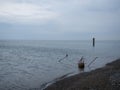 loudy weather at sea. An atmosphere of sadness and destruction. The remains of a concrete structure stick out of the water. After Royalty Free Stock Photo