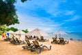 Lounge area with umbrellas and sun longers on a sandy beach against the blue sky