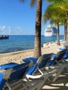 Lounge chairs on the beach in Cozumel, Mexico with a cruise ship in the background;