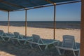 Lounge chairs on the beach. Empty resort. Sun beds under cover on the coast. Idyllic place for summer relaxation. Royalty Free Stock Photo