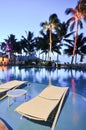 Lounge chairs by swimming pool at night time Royalty Free Stock Photo