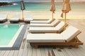 Lounging Sunbeds on Swimming Pool Wooden Deck with Seascape Background