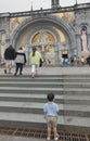 Lourdes, France, 24 June 2019: Little boy in front of the richly decorated entrance to the Rosary Basilica in Lourdest Royalty Free Stock Photo