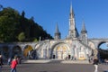 Square with people in front of Sanctuary of Our Lady in Lourdes, France. Famous religious centre of pilgrims.