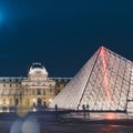 Louvre museum in Paris at night with red lightning on the pyramid
