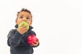 lovable African American little boy with curly hair looking uo eating a green apple and holding a red apple studio shot Royalty Free Stock Photo