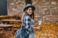 Lovable white girl in checkered shirt holding smartphone and cup of coffee in september park. Romantic lady with Royalty Free Stock Photo